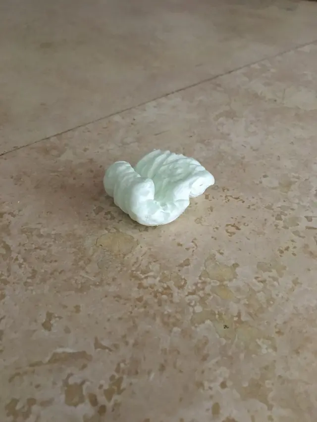 A small pale carved object resting alone on a tiled floor.