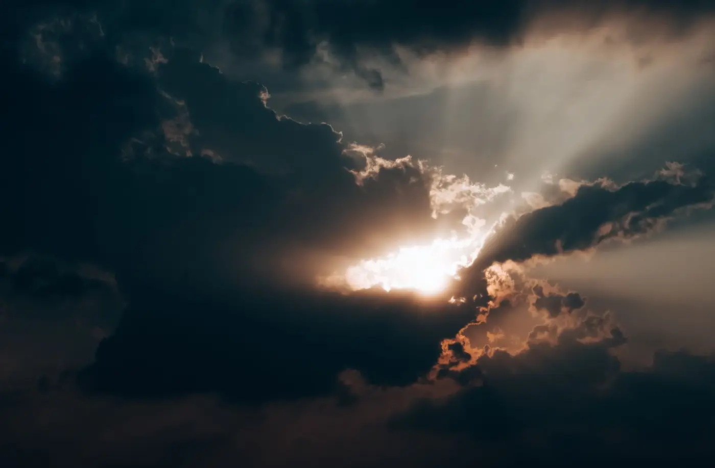 A single beam of sunlight breaking through a wall of dark storm clouds.